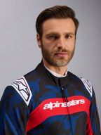 Tuta Alpinestars KMX-9 V3 Graphic 5, tuta da kart in Navy Red, con motivo grafico mimetico blu e nero, striscia orizzontale rossa con scritta alpinestars bianca sul petto e loghi bianchi sulle spalle, indossata da un modello in studio