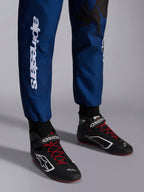 Tuta Alpinestars KMX-9 V3 Graphic 5, Navy Rosso, primo piano della parte inferiore delle gambe e scarpe da kart, tessuto blu navy con marchio Alpinestars bianco verticale, scarpe nere con lacci rossi e loghi bianchi, abbigliamento professionale da karting
