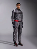 Alpinestars Tuta KMX-9 V3 Graphic 5, tuta da karting, grigio scuro e nero con motivo grafico mimetico, cintura rossa in vita con logo bianco, indossata con guanti e scarpe da corsa, abbigliamento professionale per karting
