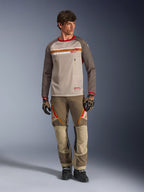 Alpinestars Maxdura Dual Jersey in Aluminum Walnut, maglia da moto adventure con busto in mesh color sabbia e maniche marroni, caratterizzata da colletto rosso e striscia orizzontale sul petto con logo Alpinestars, indossata con pantaloni e guanti adventure coordinati.