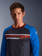 Alpinestars Maxdura Dual Jersey, grigio scuro e blu reale, indossata da un modello, caratterizzata da un busto in rete, maniche blu reale con imbottitura integrata e tasche verticali sul petto con cerniera e marchio Alpinestars sul petto.