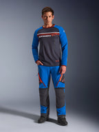 Alpinestars Maxdura Dual Jersey, maglia da moto, grigio scuro e blu reale, torso in rete con maniche imbottite e tasche sul petto con cerniera, logo Alpinestars bianco e arancione, indossata con pantaloni adventure abbinati e stivali neri