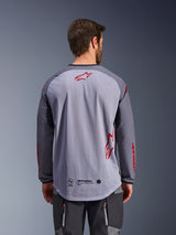 Alpinestars Maxdura Dual Jersey, vista posteriore, grigio medio e grigio scuro, con retro in rete traspirante, loghi a stella Alpinestars rossi, maniche lunghe e orlo posteriore allungato, abbigliamento per moto adventure
