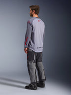 Alpinestars Maxdura Dual Jersey, maglia tecnica grigio chiaro con loghi Alpinestars rossi, vista posteriore con torso in rete e maniche lunghe, abbinata a pantaloni tecnici antracite e stivali da moto neri