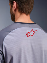 Alpinestars Maxdura Dual Jersey in Grigio Medio e Grigio Scuro, primo piano della parte superiore della schiena e del colletto, piccolo logo Alpinestars a stella rosso su tessuto a rete traspirante grigio chiaro, bordo del collo grigio scuro, progettata per la guida adventure off-road
