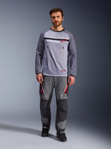 Alpinestars Maxdura Dual Jersey, grigio medio e grigio scuro, maglia da moto adventure con torso in rete e tasche sul petto con cerniera, maniche resistenti all'abrasione con imbottitura integrata, indossata con pantaloni tecnici grigi coordinati con dettagli rossi, abbigliamento tecnico per fuoristrada