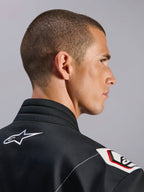 Alpinestars Kart Indoor V2 Suit, nero, vista ravvicinata del colletto ergonomico e del design della spalla derivato dalla Formula 1, con logo Alpinestars bianco e dettagli d'ispirazione racing su resistente tessuto twill