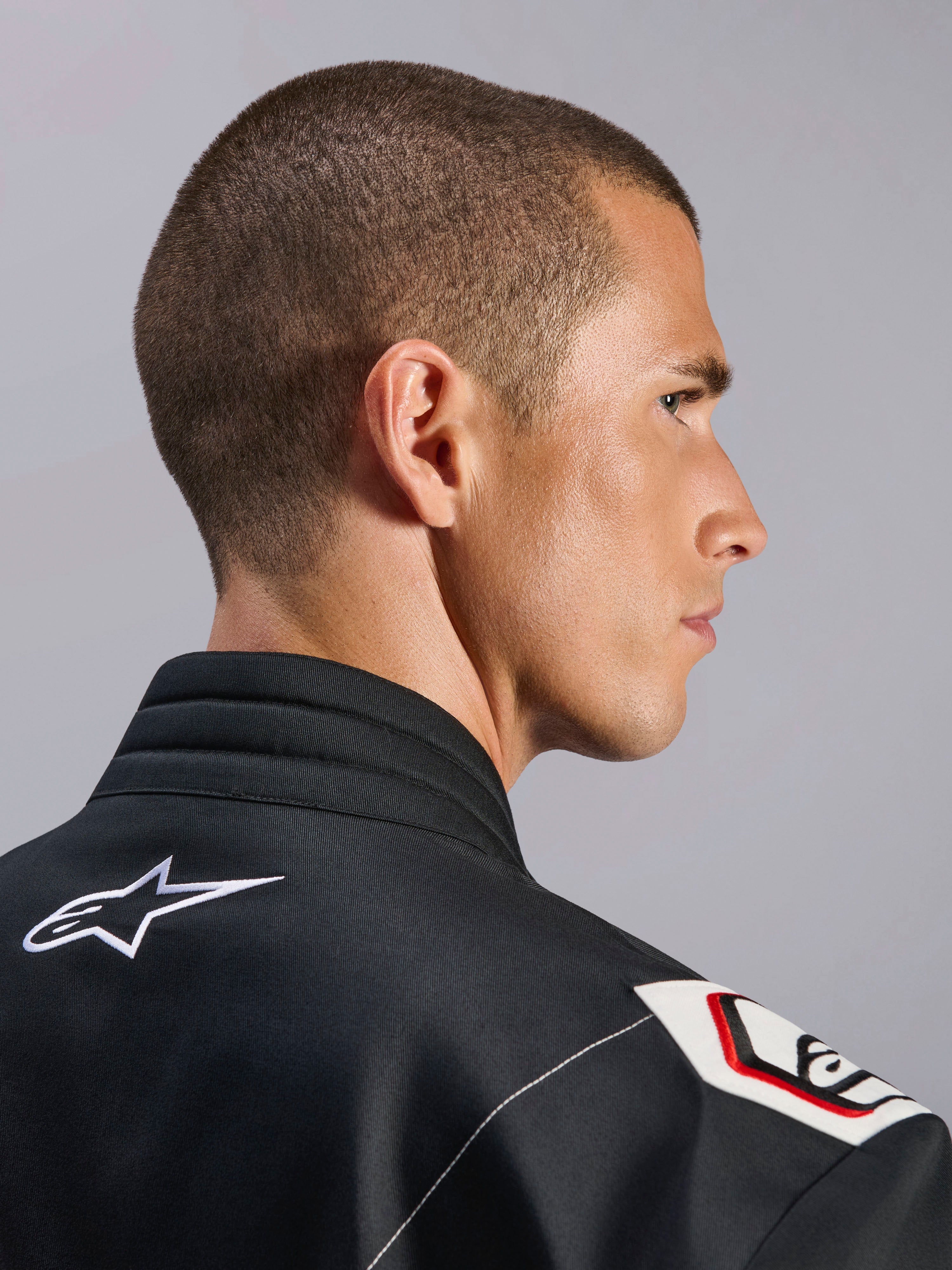 Alpinestars Kart Indoor V2 Suit, nero, vista ravvicinata del colletto ergonomico e del design della spalla derivato dalla Formula 1, con logo Alpinestars bianco e dettagli d'ispirazione racing su resistente tessuto twill