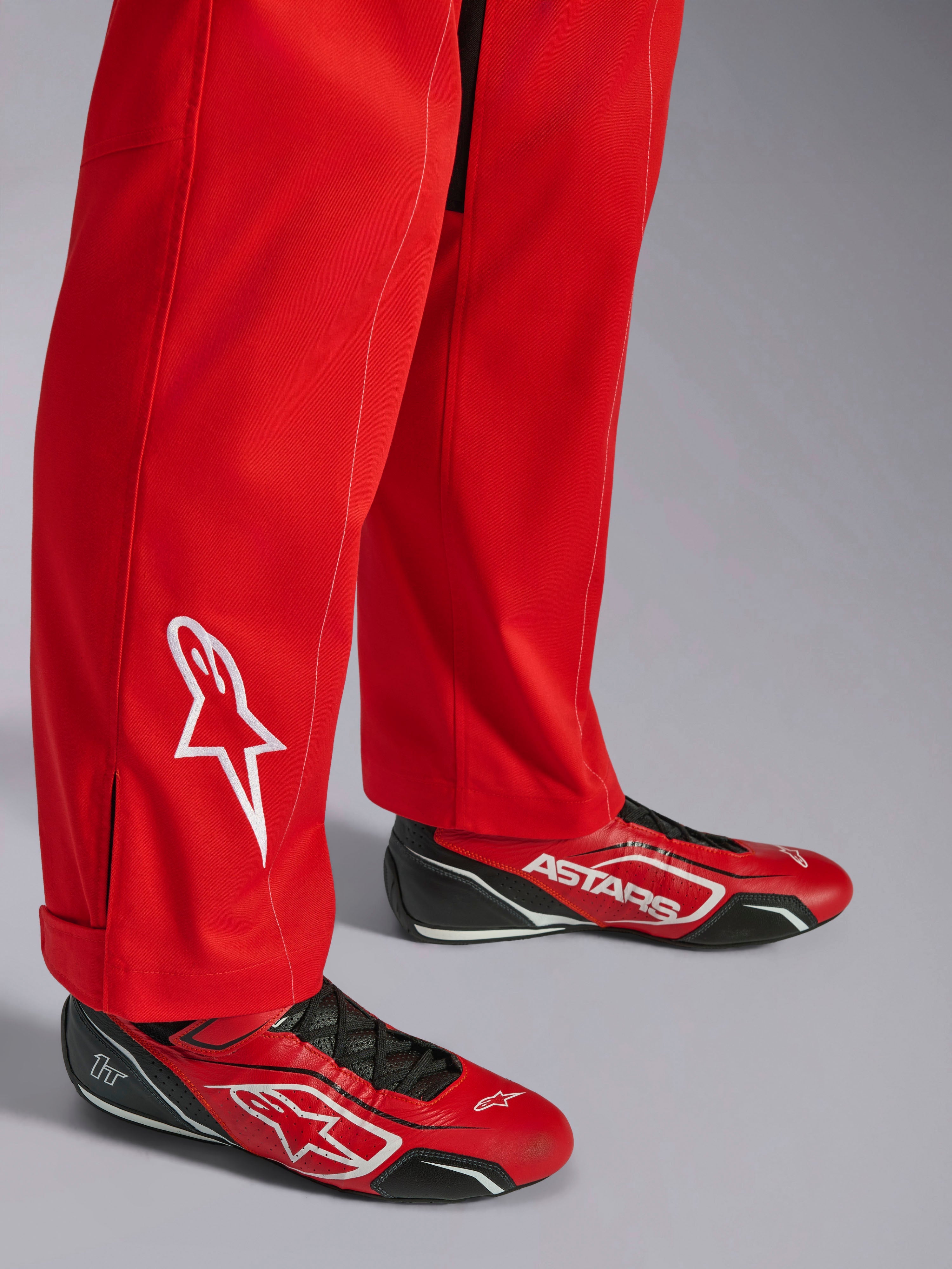 Alpinestars Kart Indoor V2 Suit, rossa, dettaglio fondo gamba con logo a stella bianco ricamato, indossata con scarpe da kart rosse e nere coordinate, materiale twill in policotone a strato singolo per karting ricreativo