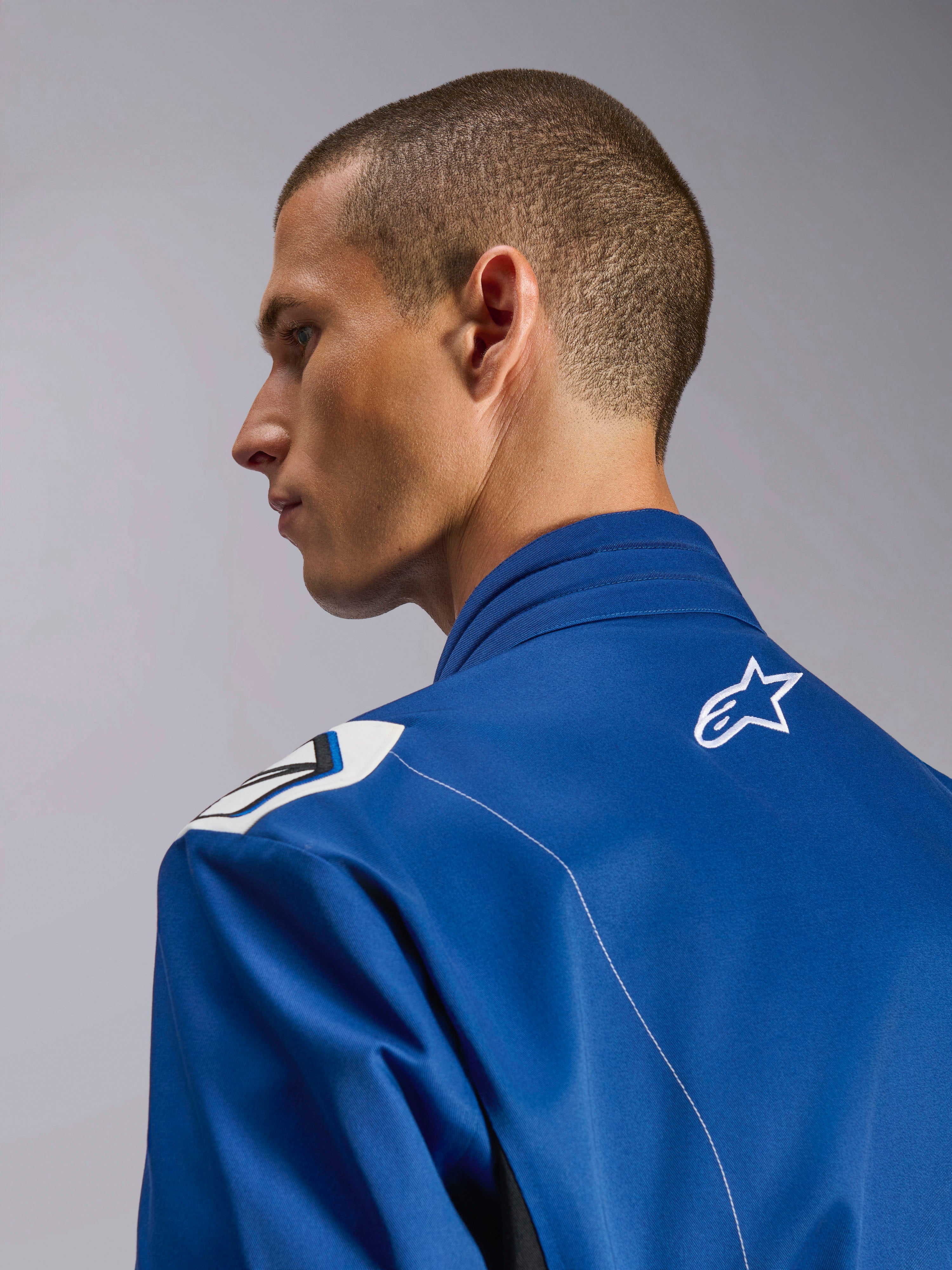 Alpinestars Kart Indoor V2 Suit, tuta da kart blu, primo piano del profilo laterale del colletto ergonomico e della parte superiore della schiena con logo a stella bianco, con design delle spalle ispirato alla Formula 1 e costruzione in twill di policotone resistente.
