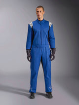 Modello che indossa la tuta Alpinestars Kart Indoor V2 in blu, tuta da kart intera con loghi a stella bianchi su spalle e stinchi, cuciture a contrasto bianche, cintura elastica in vita, abbinata a guanti da corsa e calzature neri, progettata per l'uso ricreativo in pista