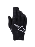 Guanti Alpinestars Supertech MX, guanti da motocross, nero e bianco, vista del dorso con un grande logo Astars bianco, perforazioni laser per la ventilazione e design ergonomico senza cuciture per gare fuoristrada