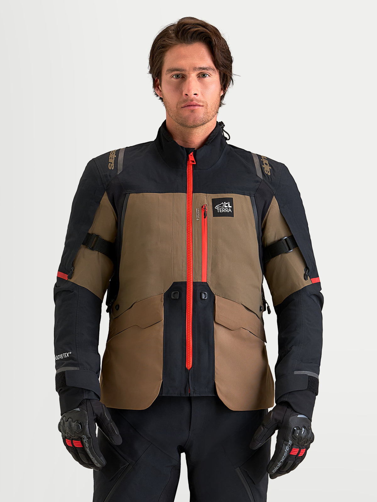 Alpinestars St 7 V 2 2 L Gore Tex Giacca, giacca da moto adventure da uomo in marrone noce e nero, con guscio GORE-TEX impermeabile, cerniera centrale rosso vivo e protezioni CE, indossata da un modello