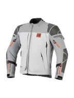 Giacca Alpinestars Nazca 3L GORE-TEX PRO, giacca da moto adventure, grigio scuro e grigio medio con dettagli delle cerniere arancioni, logo All Terra sul petto, rinforzi in Superfabric su spalle e gomiti, molteplici aperture di ventilazione con cerniera, design touring robusto