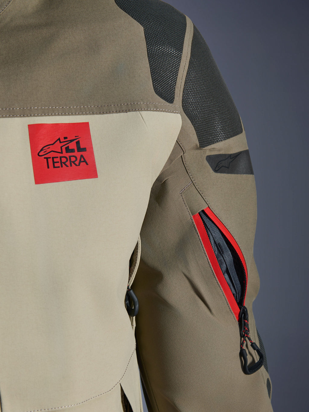 Giacca Alpinestars Nazca 3L GORE-TEX PRO, Walnut Rock Brown, dettaglio della spalla posteriore e della manica, patch logo 'ALL TERRA' rossa, pannelli sulle spalle in Superfabric nero testurizzato, presa d'aria sulla manica con cerniera e bordo rosso, abbigliamento premium per motociclismo d'avventura