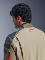 Giacca Alpinestars Nazca 3L GORE-TEX PRO, giacca da avventura Walnut Rock Brown, primo piano della schiena e della spalla, logo a stella rosso sul collo, pannelli di rinforzo grigi testurizzati, costruzione in tessuto resistente per la guida in moto