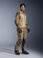 Alpinestars Nazca 3L GORE-TEX PRO Jacket, Walnut Rock Brown, giacca da moto adventure indossata con pantaloni coordinati e guanti neri, con rinforzi grigio scuro, dettagli delle cerniere rossi e guscio laminato ad alte prestazioni.