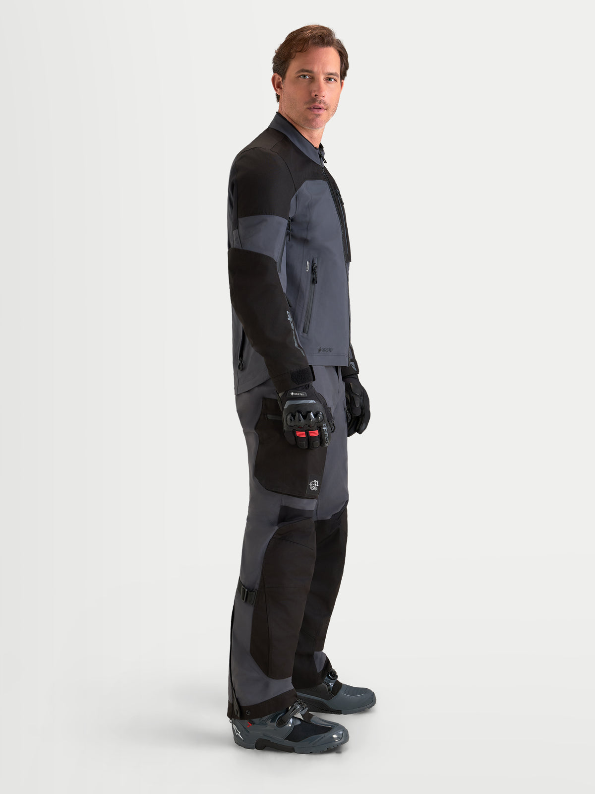 Alpinestars Arenis Gore-Tex Gear Set, completo da moto adventure touring da uomo in nero e grigio scuro, vista laterale su un modello che indossa l'equipaggiamento coordinato, struttura in tessuto GORE-TEX impermeabile