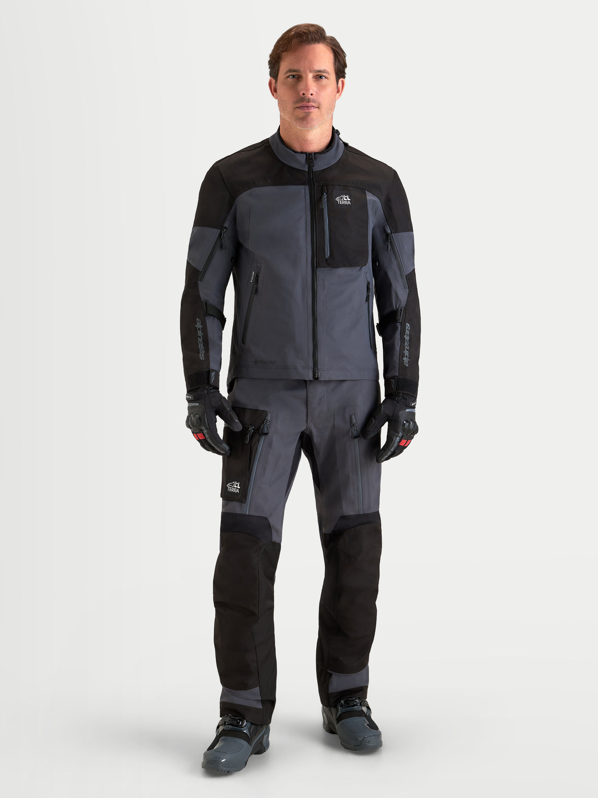 Alpinestars Arenis Gore-Tex Gear Set, completo da moto adventure da uomo in nero e grigio scuro, vista frontale a figura intera su un modello che indossa abbigliamento da guida impermeabile all-terrain