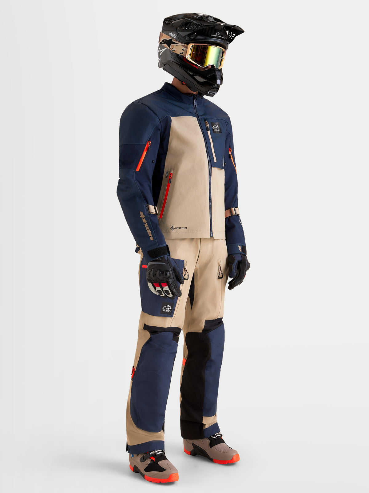 Alpinestars Arenis Gore-Tex Giacca, giacca da moto adventure da uomo in blu navy e alluminio, indossata da un pilota in equipaggiamento completo coordinato con casco, maschera e guanti