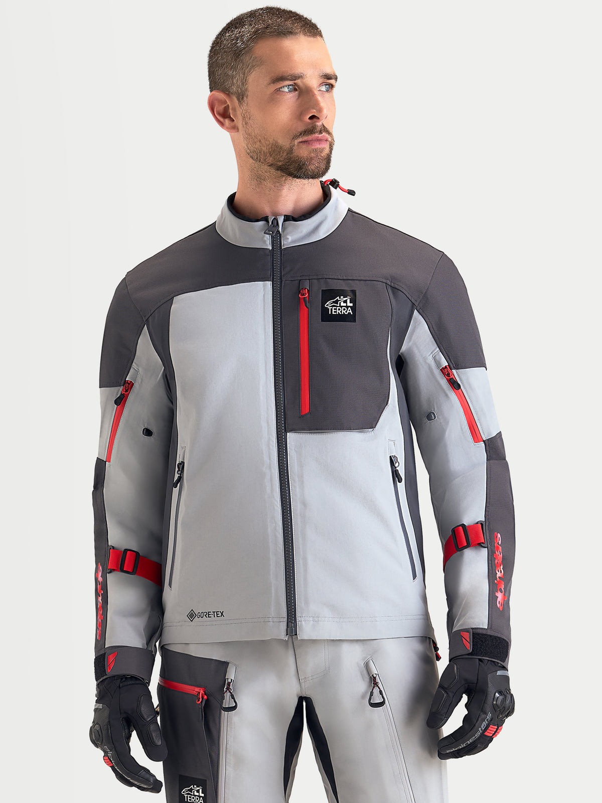Alpinestars Arenis Gore-Tex Giacca, giacca da moto adventure da uomo in grigio medio, grigio scuro e nero, vista frontale indossata da un modello che mostra la struttura in tessuto impermeabile e la tasca sul petto con zip