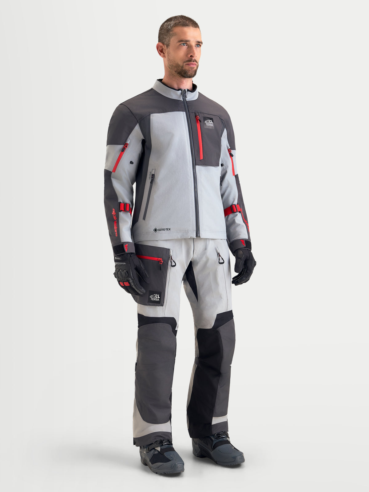 Alpinestars Arenis Gore-Tex Gear Set, completo da moto adventure touring da uomo in grigio chiaro e grigio scuro con dettagli rossi, vista frontale su un modello che indossa abbigliamento tecnico impermeabile coordinato