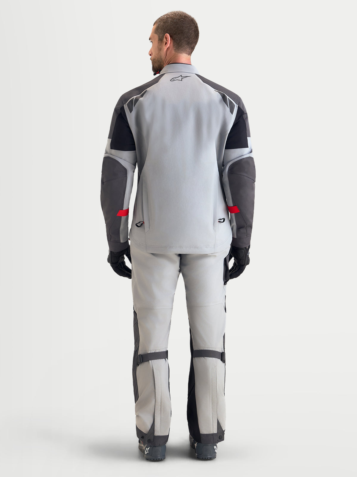 Alpinestars Arenis Gore-Tex Gear Set, completo da moto adventure da uomo in grigio chiaro e grigio scuro, vista posteriore su un modello che mostra la struttura in tessuto GORE-TEX impermeabile e la vestibilità ergonomica