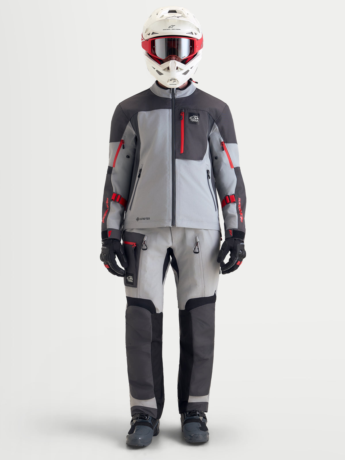 Alpinestars Arenis Gore-Tex Gear Set, completo da moto adventure da uomo in grigio, grigio scuro e rosso, vista frontale di un modello che indossa abbigliamento coordinato e casco, equipaggiamento di guida all-terrain impermeabile