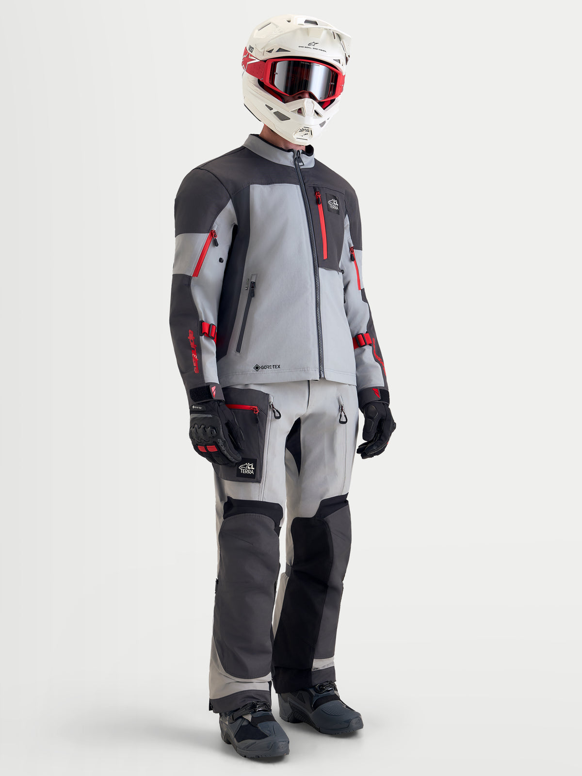 Alpinestars Arenis Gore-Tex Gear Set, completo da moto adventure da uomo in grigio, grigio scuro e rosso, vista a figura intera su un modello che indossa casco coordinato, maschere, guanti e stivali, abbigliamento da guida impermeabile all-terrain