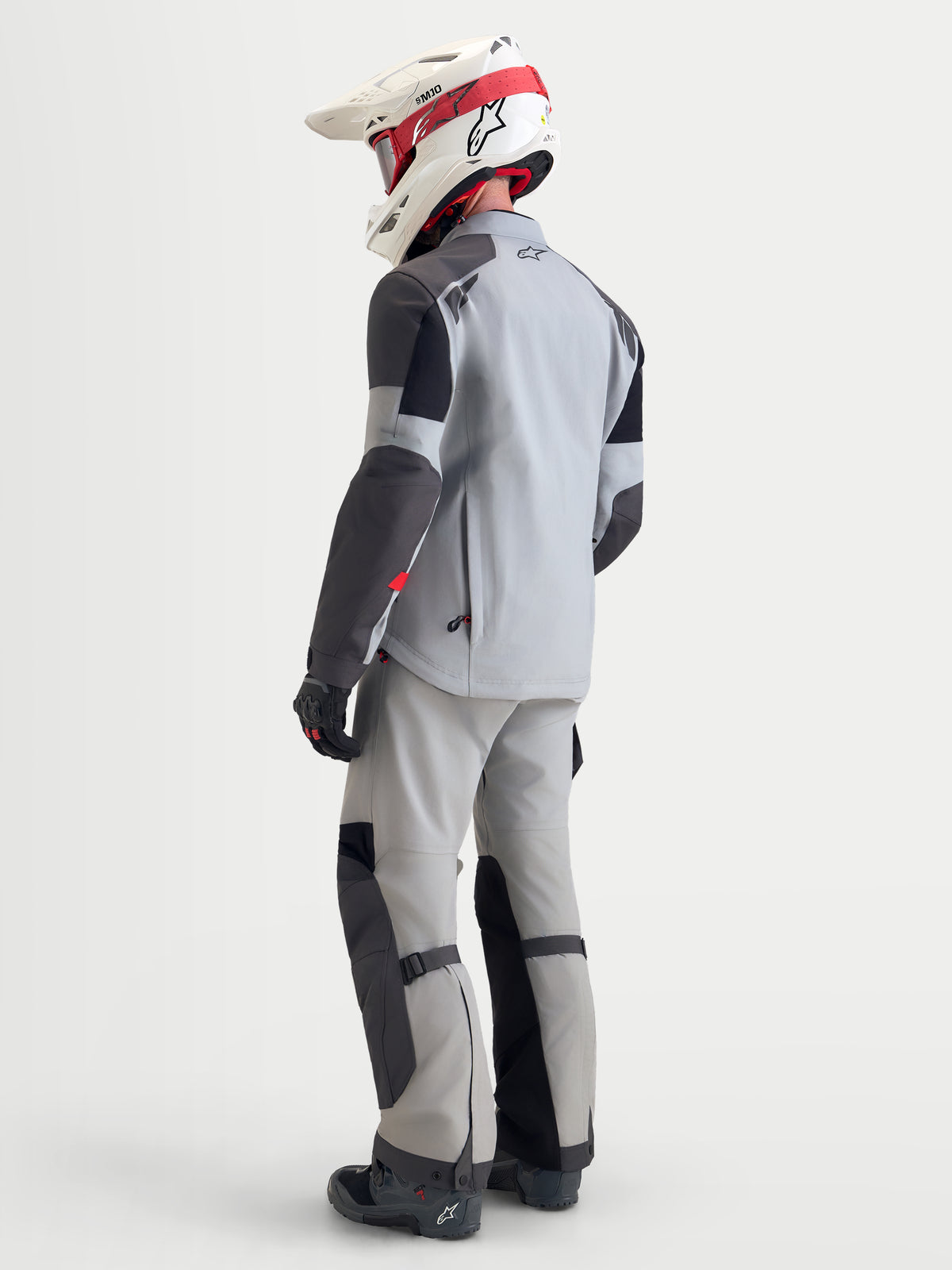 Alpinestars Arenis Gore-Tex Gear Set, completo da moto adventure da uomo in grigio chiaro e nero, vista posteriore di un modello che indossa abbigliamento e casco coordinati, con struttura in tessuto impermeabile