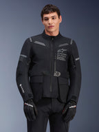 Giacca Alpinestars ST-7 2L GORE-TEX, giacca da moto touring, nero e grigio scuro, con logo Alpinestars Exploration Equipment sul petto, ampie tasche cargo impermeabili, logo GORE-TEX sulla manica, design robusto ideale per l'avventura e dettagli riflettenti