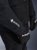 Giacca Alpinestars ST-7 2L GORE-TEX, nero e grigio scuro, primo piano della manica con logo GORE-TEX bianco, indossata con guanti da moto adventure neri, abbigliamento da moto impermeabile