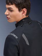 Giacca Alpinestars ST-7 2L GORE-TEX, giacca da moto nera e grigio scuro, vista ravvicinata del colletto con regolazione a cordino elastico ed etichetta Tech-Air, con dettagli riflettenti grigi e logo del brand sulla spalla.