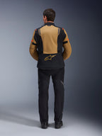 Giacca Alpinestars ST-7 2L GORE-TEX, giacca da moto adventure, Gobi Brown e nero, vista posteriore che mostra la pannellatura ergonomica e il logo Alpinestars, indossata con pantaloni da moto e stivali neri, abbigliamento da touring impermeabile