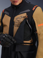 Giacca Alpinestars ST-7 2L GORE-TEX, giacca da moto adventure touring, Gobi Brown e nero, primo piano del pannello di ventilazione sul petto aperto che rivela la rete traspirante, con marchio Alpinestars Exploration Equipment e accenti arancioni