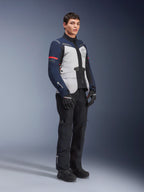 Giacca Alpinestars ST-7 2L GORE-TEX, colorazione Ice Gray, blu scuro e nero con accenti rossi, indossata da un modello con pantaloni da moto e guanti neri, abbigliamento professionale da moto adventure touring