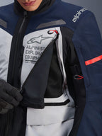 Giacca Alpinestars ST-7 2L GORE-TEX, giacca adventure touring, Ice Gray, blu scuro e nero, vista dettagliata del pannello di ventilazione sul petto aperto che mostra la rete nera, con logo Alpinestars Exploration Equipment e tiranti con accenti rossi