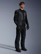 Modello che indossa la giacca Alpinestars ST-7 2L GORE-TEX in Deep Gray Black e Dark Khaki, abbinata a pantaloni e guanti adventure neri coordinati, con guscio laminato impermeabile, tasche cargo e branding tecnico, ideale per l'adventure touring.