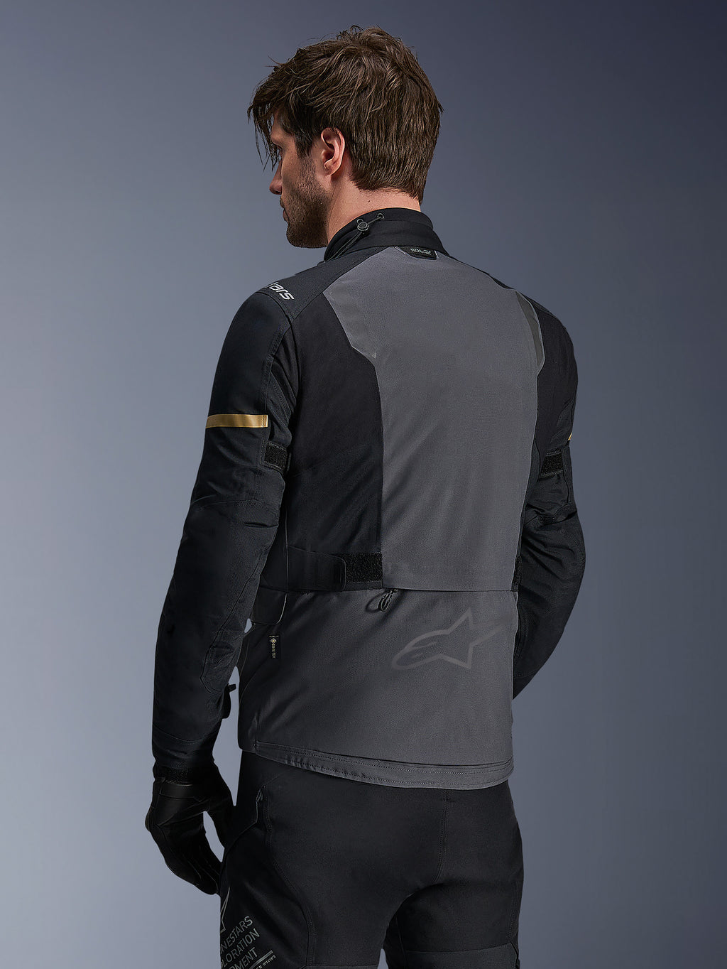 Alpinestars Giacca ST-7 2L GORE-TEX, giacca da moto, grigio scuro, nero e cachi scuro, vista posteriore che mostra l'ampio pannello posteriore grigio con marchio discreto, maniche nere con accenti cachi dorati, design in tessuto impermeabile per l'avventura