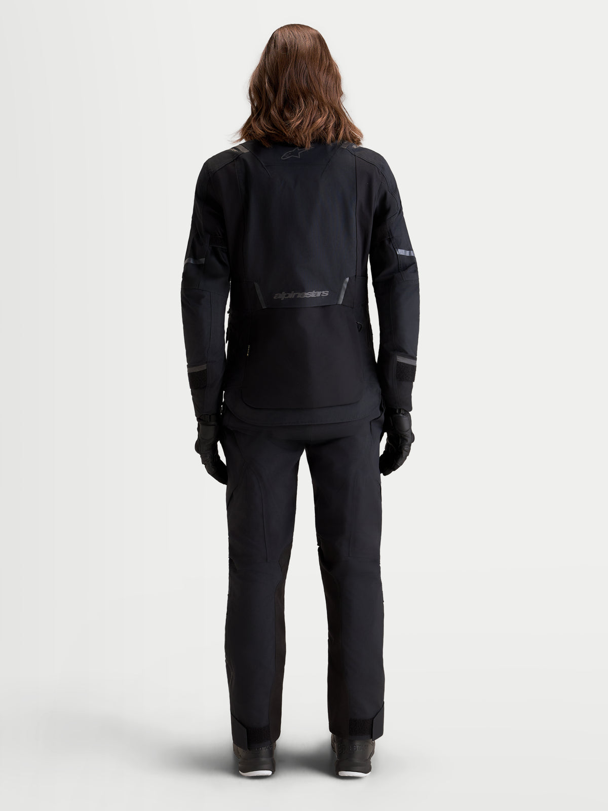 Alpinestars Stella ST-7 V2 2L Gore-Tex Giacca, giacca da moto adventure da donna in nero, vista posteriore su una modella che mostra la struttura in tessuto impermeabile e i dettagli riflettenti