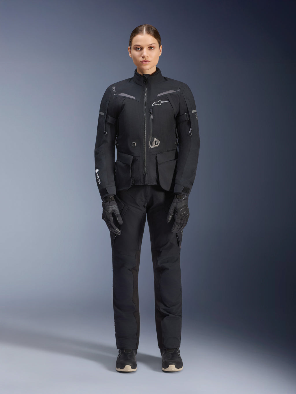 Giacca Alpinestars Stella ST-7 2L GORE-TEX, giacca da moto touring da donna, nero e grigio scuro, indossata con pantaloni e guanti coordinati, dotata di guscio laminato impermeabile, inserti riflettenti e design ergonomico adventure