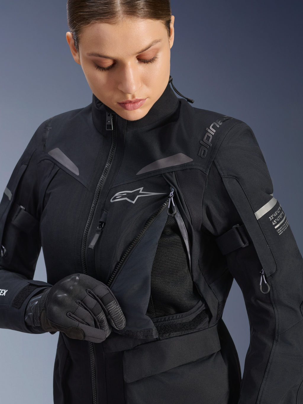 Giacca Alpinestars Donna Stella ST-7 2L GORE-TEX in Nero Grigio Scuro, vista dettagliata del pannello di ventilazione sul petto aperto con fodera in rete, logo Alpinestars e branding sulla spalla, progettata per l'adventure road-touring