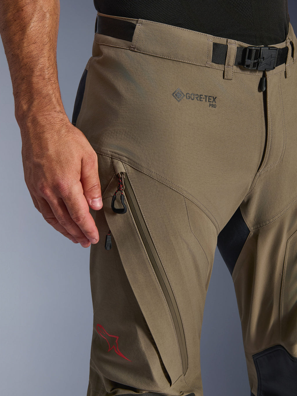 Alpinestars Nazca 3L GORE-TEX PRO Pants, pantaloni tecnici da moto adventure, Walnut Black, dettaglio di fianco e coscia con branding GORE-TEX PRO, tasca cargo diagonale con zip, cintura regolabile con fibbia e logo a stella rosso.