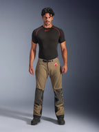 Modello che indossa pantaloni Alpinestars Nazca 3L GORE-TEX PRO in marrone noce e nero, abbigliamento tecnico da moto adventure con rinforzi sulle ginocchia in Superfabric e fibbia magnetica in vita, abbinati a una maglia base layer Alpinestars nera, vista frontale in studio.