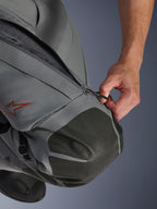 Alpinestars Nazca 3L GORE-TEX PRO Pants, pantaloni da moto adventure, grigio scuro e nero, primo piano di una mano che apre la presa d'aria con zip sulla coscia, con rinforzi per le ginocchia in Superfabric testurizzato e logo a stella Alpinestars rosso, costruzione in tessuto tecnico per protezione in ogni condizione atmosferica