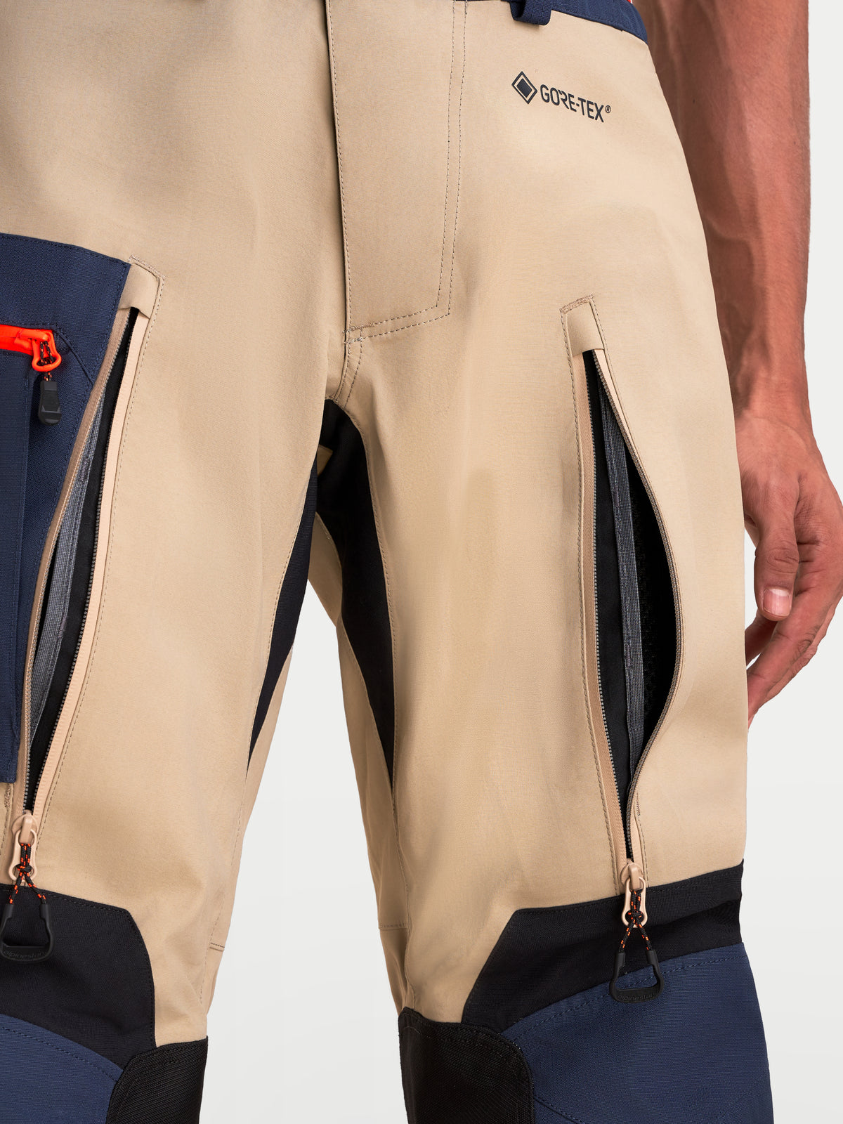 Alpinestars Arenis Gore-Tex Pantaloni, pantaloni da moto adventure da uomo, vista ravvicinata delle prese d'aria con cerniera sulle cosce e logo GORE-TEX in beige, blu scuro e nero