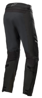 Pantaloni Alpinestars Road Tech GORE-TEX Corti, nero, vista posteriore a 3/4 con cerniera di collegamento in vita, cinturini regolabili sui polpacci e rinforzi in nylon balistico, abbigliamento da touring avventuroso impermeabile