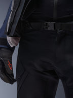 Pantaloni Alpinestars ST-7 2L GORE-TEX, nero, primo piano della vita con chiusura a fibbia magnetica e robusta struttura in tessuto tecnico, indossati con giacca adventure touring coordinata e guanti neri con logo rosso.