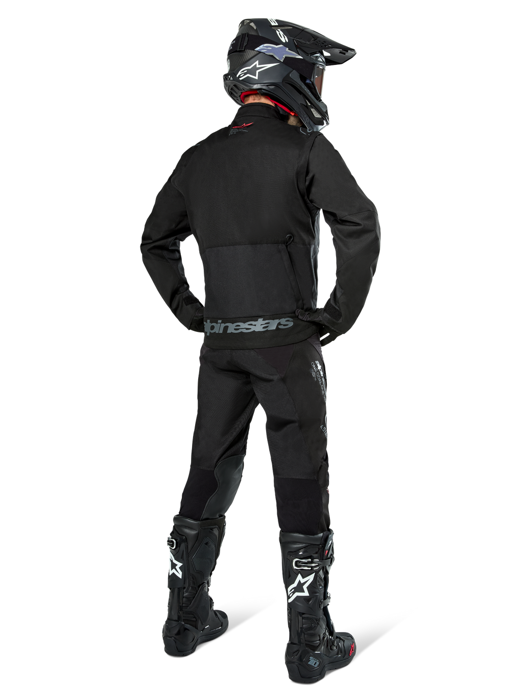 Giacca Alpinestars Pro-Dura, giacca da enduro off-road nera, vista posteriore indossata con pantaloni coordinati e stivali Tech 10 neri, caratterizzata dal prominente logo Alpinestars sulla parte bassa della schiena, costruzione in tessuto robusto per guida trail aggressiva