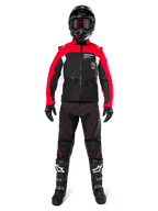 Pilota di motocross con equipaggiamento completo da fuoristrada, Giacca Alpinestars Pro-Dura in Nero, Rosso Acceso e Bianco, pantaloni neri con dettagli rossi, casco nero con maschera rossa, stivali neri e bianchi, completo coordinato per enduro e trail riding